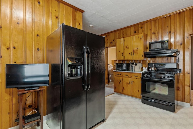 kitchen featuring exhaust hood, wooden walls, and black appliances