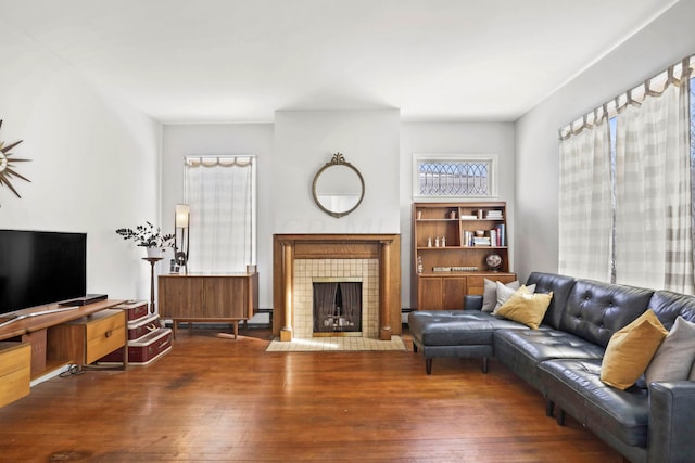 living room with dark wood-type flooring and a tile fireplace