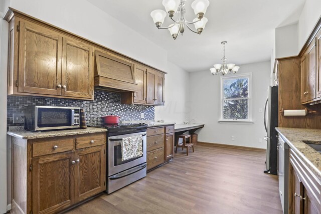 kitchen featuring hanging light fixtures, an inviting chandelier, backsplash, light hardwood / wood-style floors, and appliances with stainless steel finishes