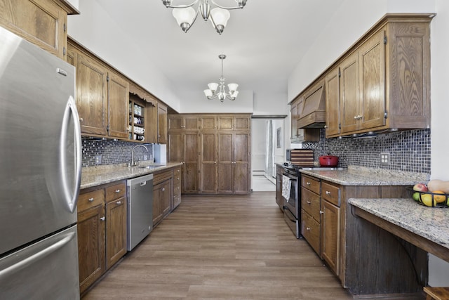 kitchen with pendant lighting, stainless steel appliances, a notable chandelier, and hardwood / wood-style floors