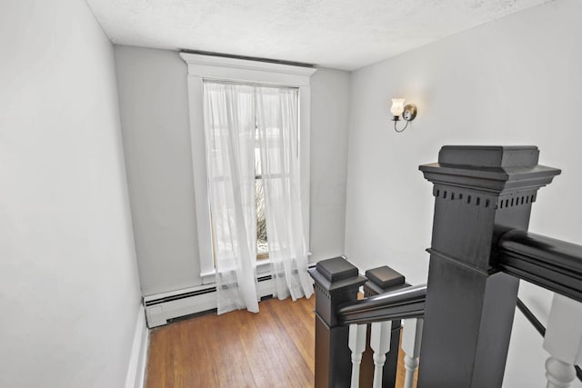 interior space featuring hardwood / wood-style floors, a textured ceiling, a baseboard radiator, and a wealth of natural light