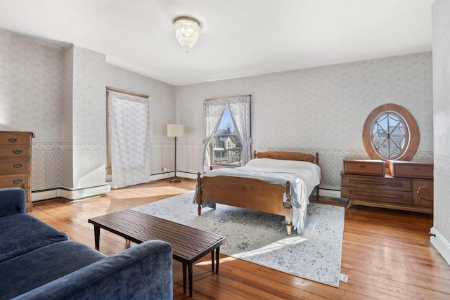 bedroom with wood-type flooring and a baseboard heating unit