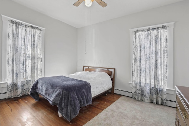 bedroom featuring ceiling fan, dark hardwood / wood-style flooring, and baseboard heating