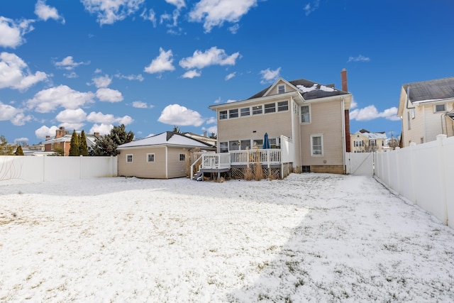 snow covered back of property with a deck