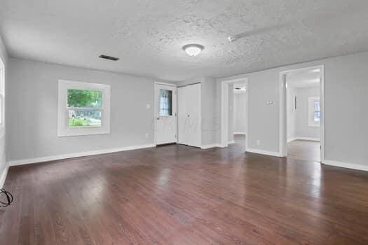 spare room featuring a textured ceiling and dark hardwood / wood-style flooring