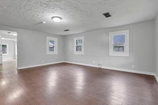 unfurnished room featuring dark wood-type flooring and a textured ceiling