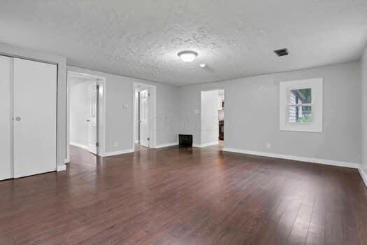 unfurnished living room featuring dark hardwood / wood-style flooring and a textured ceiling