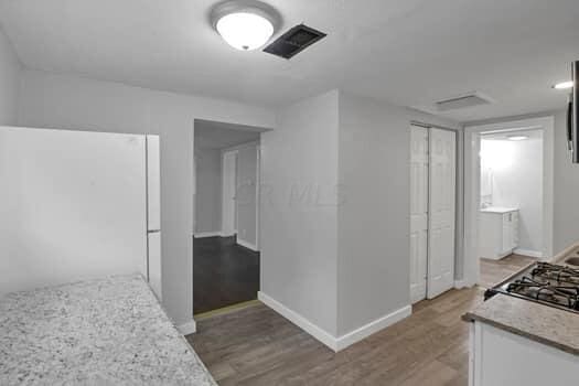 kitchen featuring hardwood / wood-style flooring, white fridge, and white cabinets