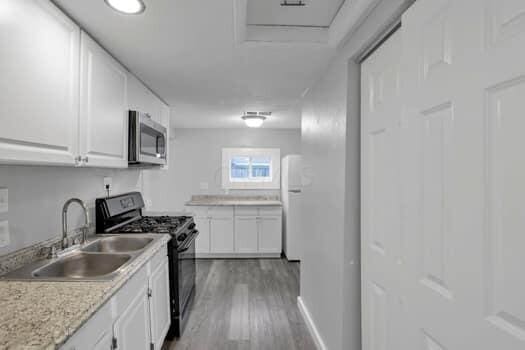 kitchen featuring white cabinetry, black gas range, white fridge, and hardwood / wood-style flooring