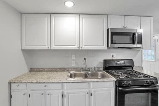 kitchen featuring white cabinetry, sink, and black gas range