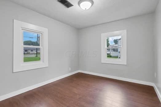 unfurnished room with dark hardwood / wood-style floors and a healthy amount of sunlight