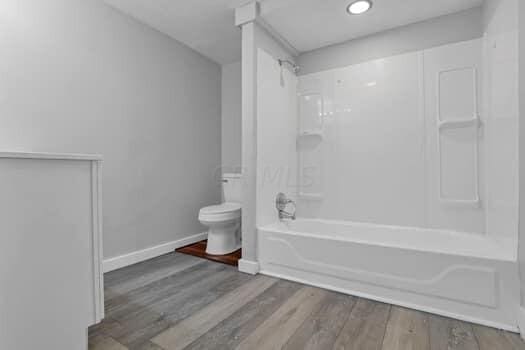 bathroom with tub / shower combination, hardwood / wood-style floors, and toilet