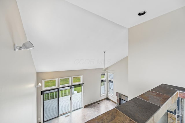 interior space featuring lofted ceiling, baseboards, a fireplace, and visible vents