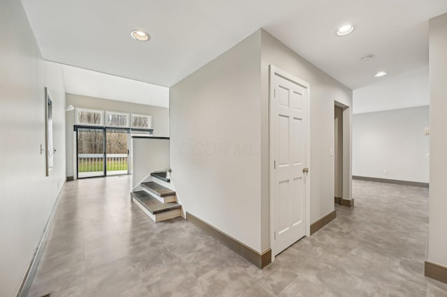 hall with recessed lighting, concrete floors, and baseboards