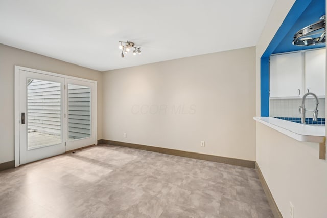 unfurnished room featuring a sink and baseboards