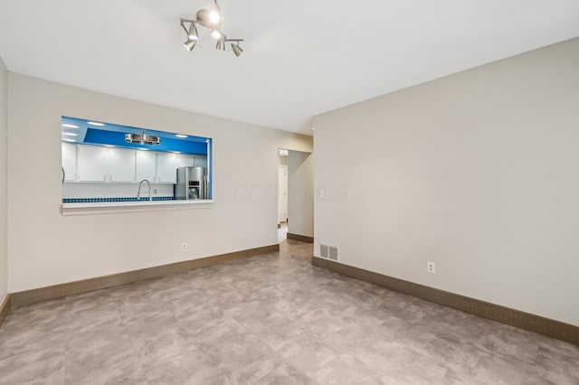 unfurnished room with a chandelier, a sink, visible vents, and baseboards