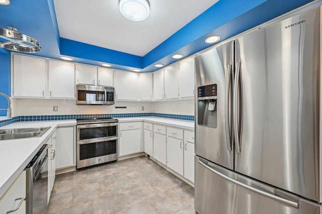 kitchen with stainless steel appliances, a sink, white cabinets, light countertops, and decorative backsplash