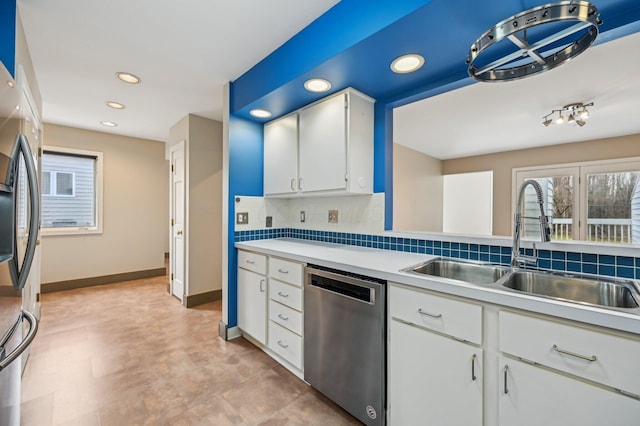 kitchen with baseboards, decorative backsplash, stainless steel appliances, light countertops, and a sink