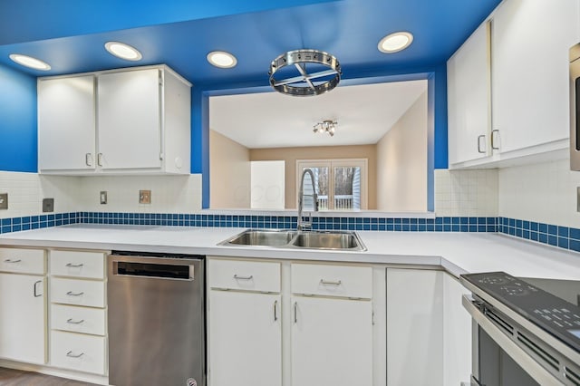 kitchen with white cabinets, light countertops, a sink, and stainless steel dishwasher