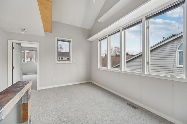 carpeted empty room with lofted ceiling, visible vents, and baseboards