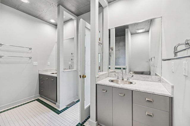 bathroom with baseboards, two vanities, a sink, and tile patterned floors