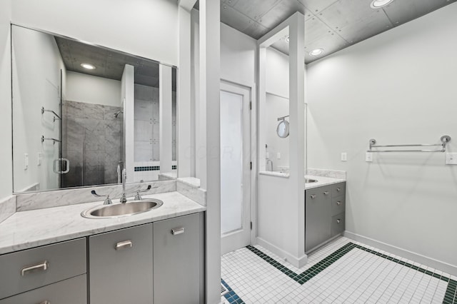 bathroom featuring a sink, a stall shower, two vanities, and baseboards