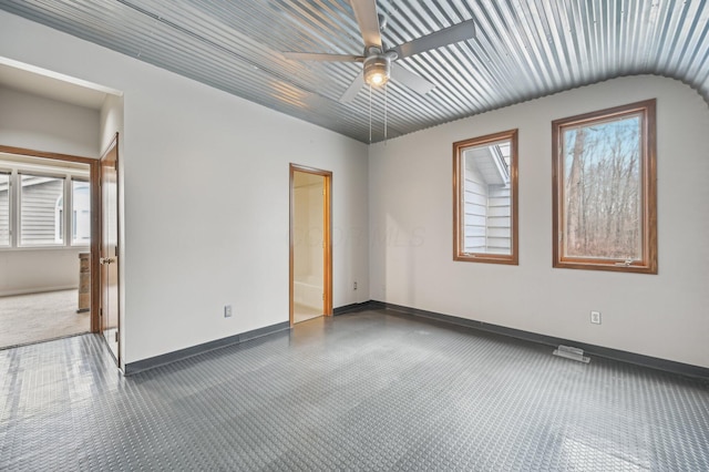 carpeted spare room with plenty of natural light, a ceiling fan, and baseboards