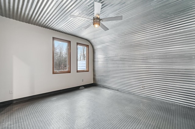 empty room with a ceiling fan and baseboards