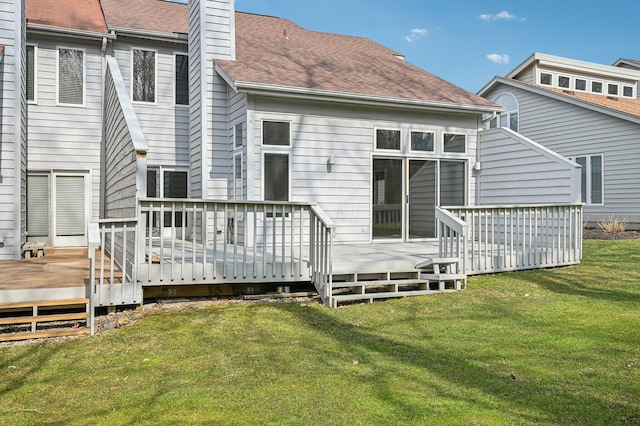 rear view of property featuring a shingled roof, a lawn, a chimney, and a wooden deck