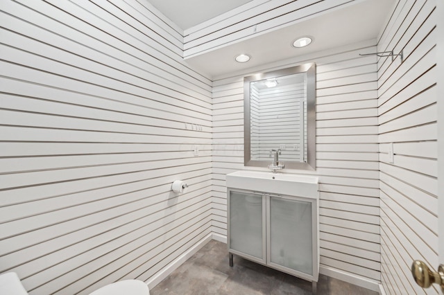 half bathroom featuring a sink, concrete floors, and toilet