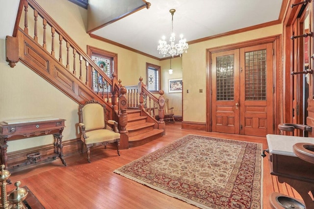 entryway featuring ornamental molding, light hardwood / wood-style floors, french doors, and an inviting chandelier