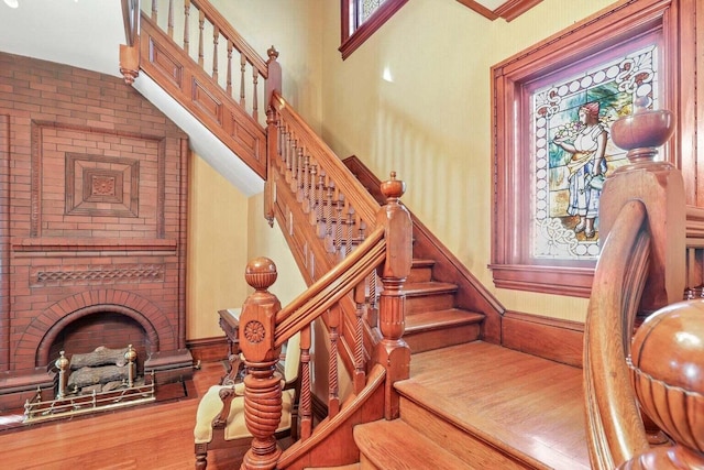 staircase featuring hardwood / wood-style floors and a brick fireplace