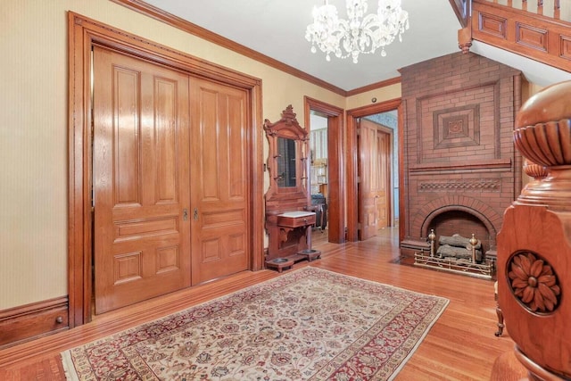 interior space with a chandelier, ornamental molding, a fireplace, and light hardwood / wood-style flooring