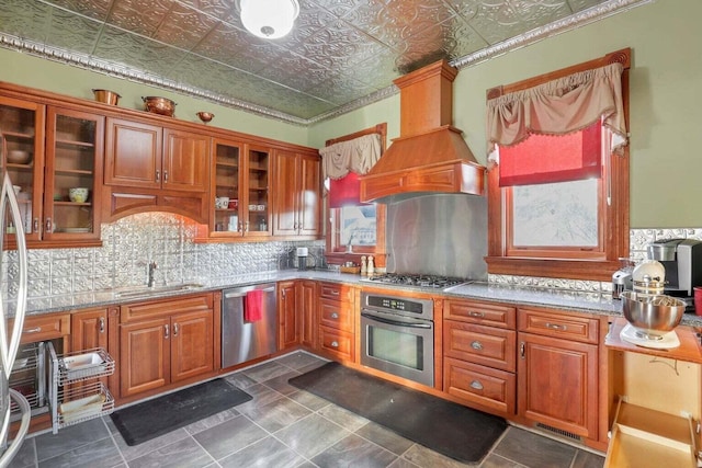 kitchen featuring custom exhaust hood, backsplash, sink, light stone counters, and stainless steel appliances