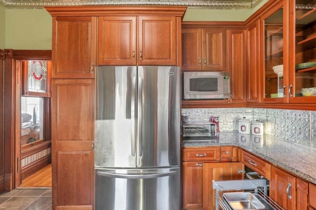 kitchen with light stone counters, dark tile patterned floors, backsplash, and appliances with stainless steel finishes