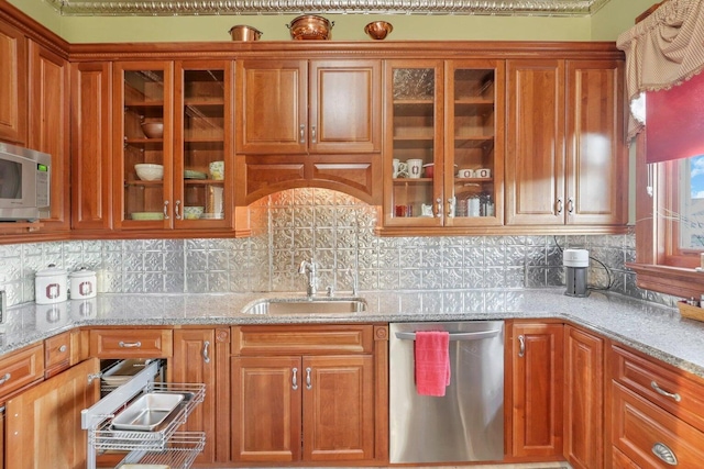 kitchen featuring light stone countertops, appliances with stainless steel finishes, backsplash, and sink