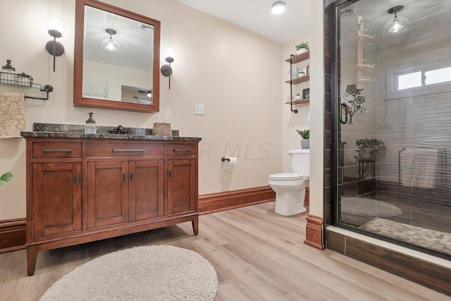 bathroom featuring hardwood / wood-style floors, vanity, toilet, and a shower with shower door