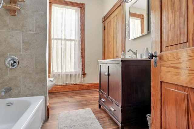 bathroom featuring a wealth of natural light, toilet, vanity, and hardwood / wood-style flooring