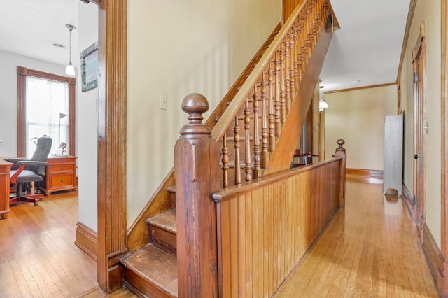 staircase with hardwood / wood-style flooring and ornamental molding