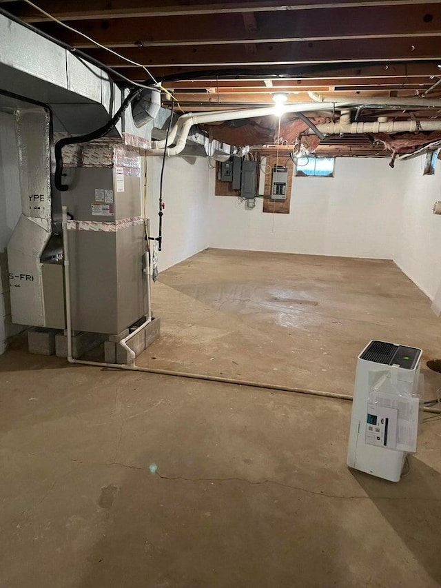 basement featuring electric panel and heating unit