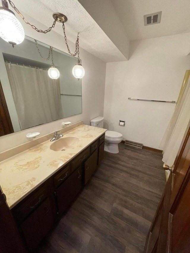 bathroom featuring vanity, wood-type flooring, a textured ceiling, and toilet