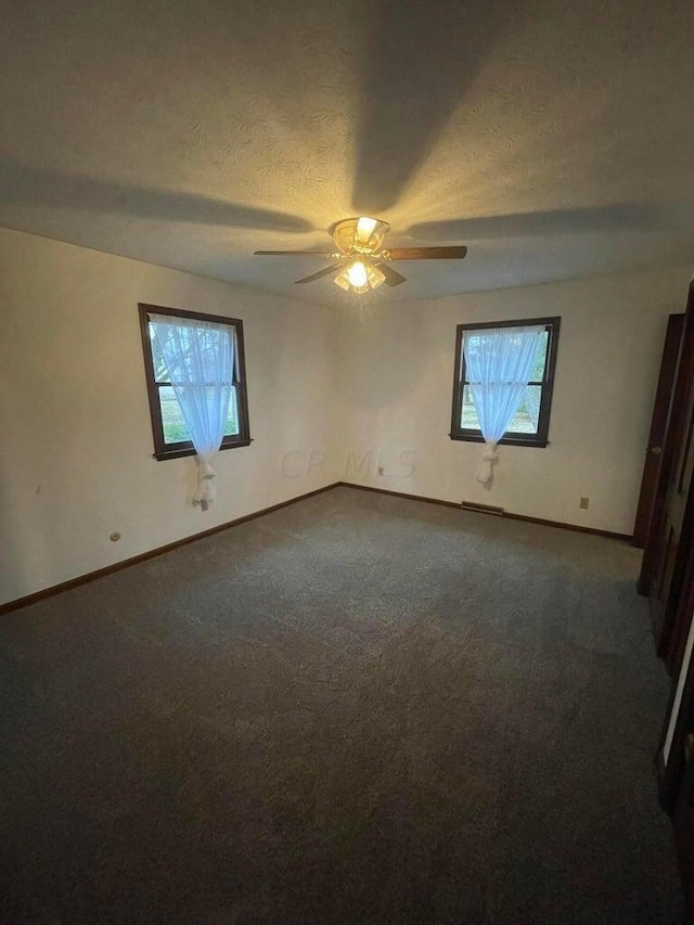 carpeted empty room with ceiling fan and a textured ceiling