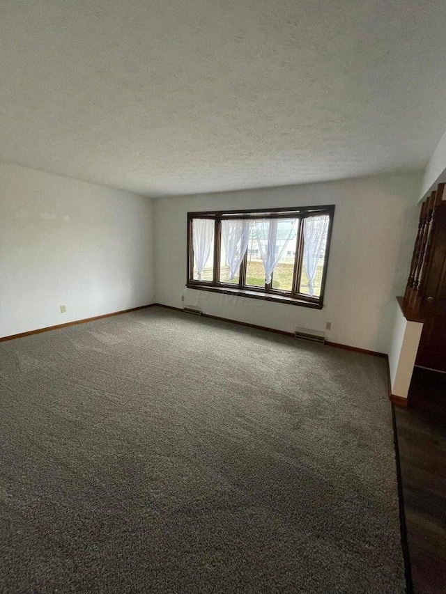 unfurnished room with dark colored carpet and a textured ceiling