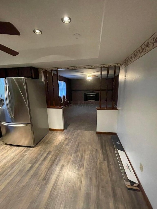 interior space featuring ceiling fan, stainless steel fridge, dark hardwood / wood-style flooring, and dark brown cabinetry