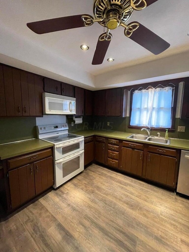 kitchen with white appliances, light hardwood / wood-style flooring, dark brown cabinetry, and sink