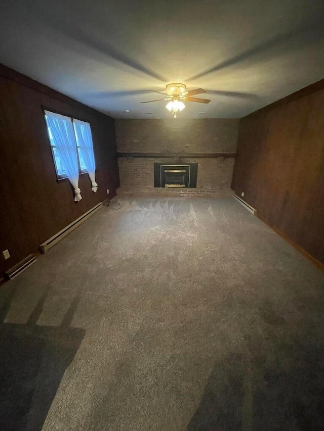 unfurnished living room featuring baseboard heating, wood walls, and carpet flooring