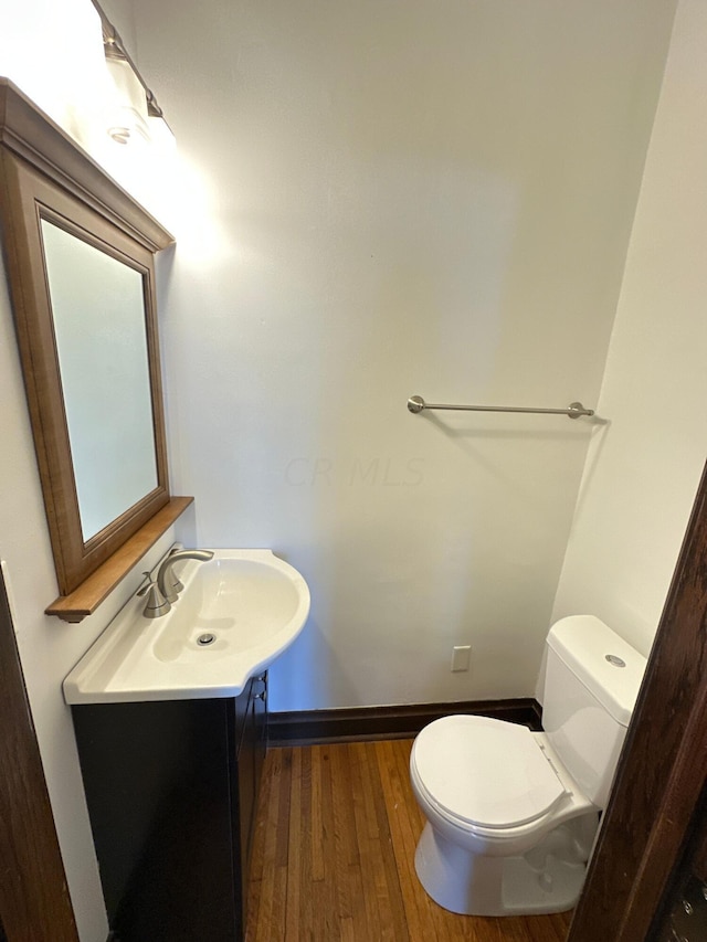 bathroom with hardwood / wood-style flooring, vanity, and toilet