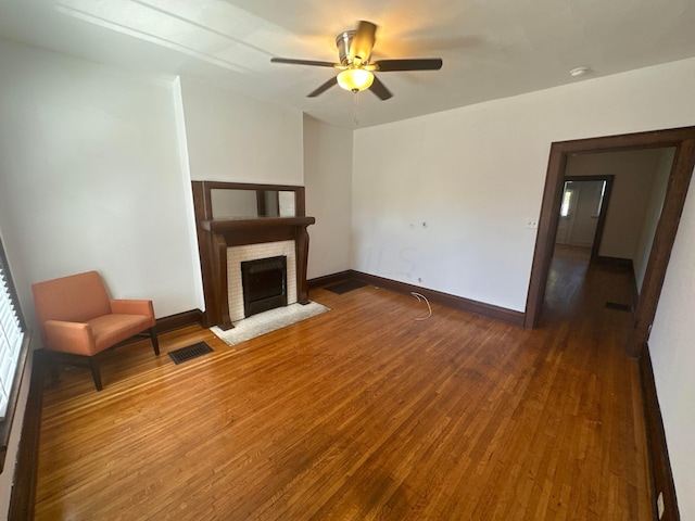 unfurnished living room with a fireplace, dark hardwood / wood-style floors, and ceiling fan