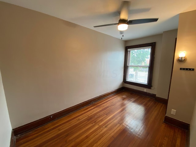 spare room with dark hardwood / wood-style flooring and ceiling fan