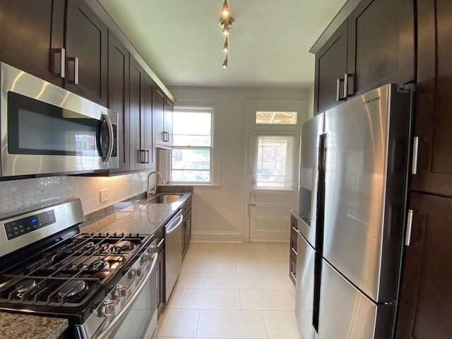 kitchen featuring backsplash, dark stone countertops, sink, and appliances with stainless steel finishes